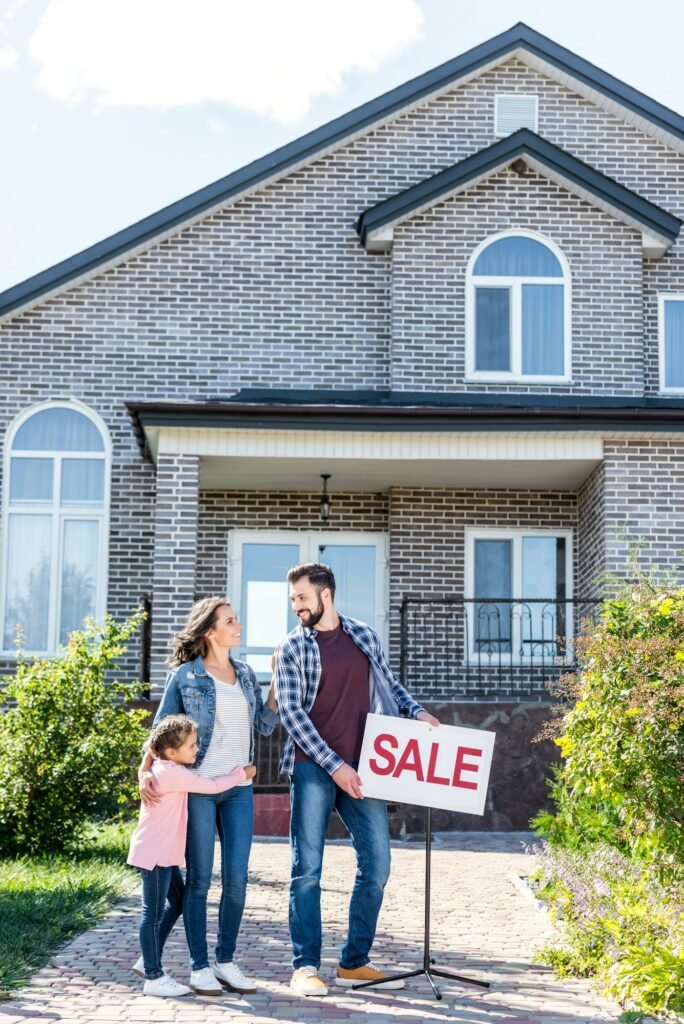 young happy family standing in front of new house on sale